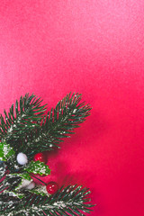 Snowy Christmas tree branch on red background, Christmas or holiday background, vintage toned