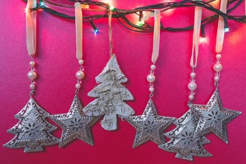 Close up view of silver vintage traditional Christmas tree decoration or ornaments hanging against red background and shining Christmas lights