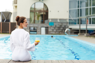 Rear view of young restful female spending day by swimming pool