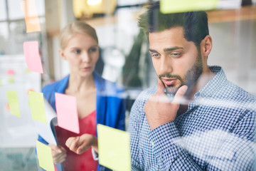 Pensive manager looking at working note while his colleague offering the best solution
