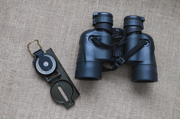 Military binoculars and compass, traveler's things, on sackcloth background