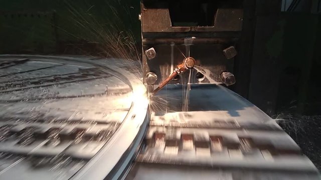 The cutting tool in the tool holder with the pouring lubricating-cooling liquid processes the titanium part on the rotating faceplate on a lathe with programmed control