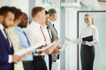 Young woman inviting one of candidates for new vacancy for interview to boardroom