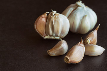 Fresh garlic put on black granite table in side view with copy space, isolated background. Food preparation concept for spices and herbs in still life idea...