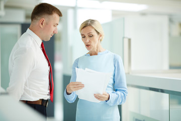 Fototapeta premium Mature employer showing some financial papers to businessman during discussion