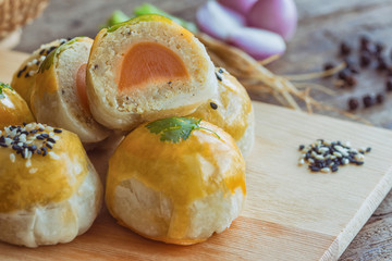 Delicious Chinese pastry or moon cake on wood cutting board with some ingredient on wooden table in side view, close up for afternoon tea or coffee break. Homemade bakery concept.