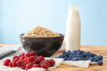 Composition with oatmeal flakes, berries and milk on light background