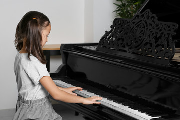Little girl playing piano indoors