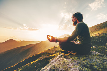 Man meditating yoga lotus pose at sunset mountains Travel Lifestyle relaxation emotional concept summer vacations outdoor harmony with nature calm scene