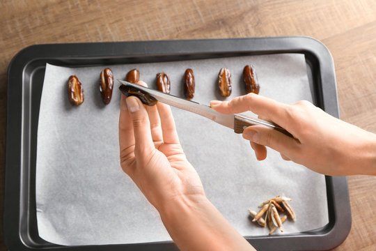 Woman removing pit from ripe date near baking tray