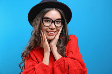 Beautiful hipster girl in red sweater on blue background