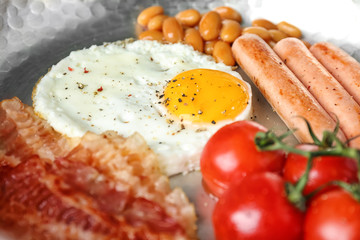 Frying pan with egg, beans, sausages, bacon and cherry tomatoes, closeup
