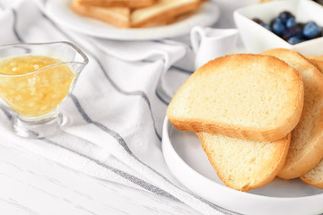 Plate with fresh crispy toasts on table