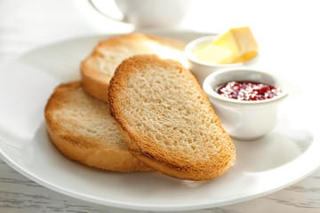 Plate with fresh crispy toasts on table