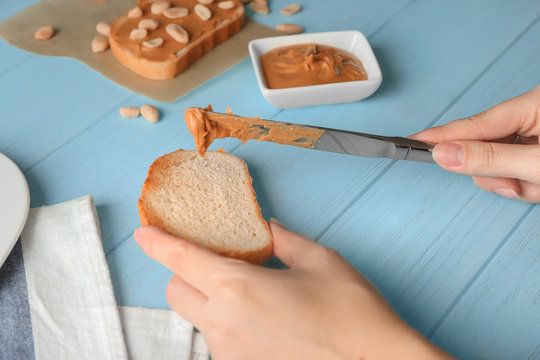 Woman spreading peanut butter on toast over table