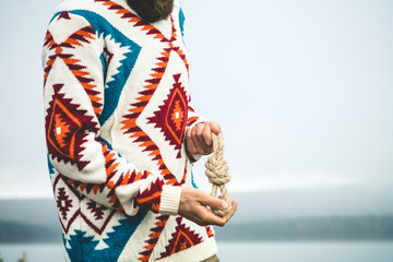 Man hands holding rope knot Travel Lifestyle survival concept wearing knitted sweater outdoor foggy nature on background