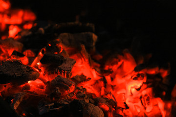 Red fire coals in the fireplace. Dark background. Smoldering firewood.