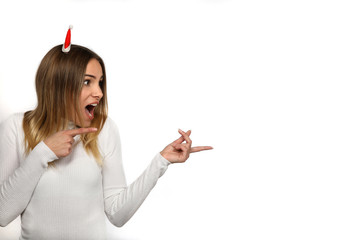 Hübsche blonde Frau mit Weihnachtsmütze begeistert zeigt in eine Richtung
