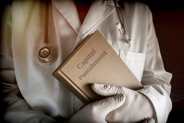 Doctor holds in a Capital Punishment book in a hospital. Conceptual image