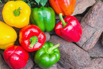 Assorted colorful varieties of sweet peppers sitting on old wooden table, rustic style, selective focus
