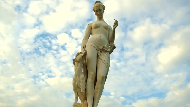A female sculpture in front of the museum Louvre in Paris recorded in timelapse mode. Clouds are passing by on a sunny day.
