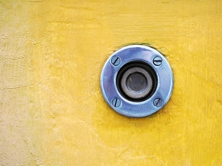 Old button, protection against accidental pressing. Panic or alarm button for emergency. Button without inscriptions on an old yellow wall with wrinkled, cracked paint