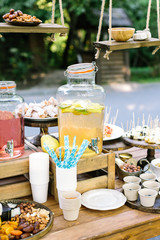 meal, summer, plesure concept. there are different types of fruit juices, nuts, dried fruits in the paper cups and spring rolls in the wooden vase on the table