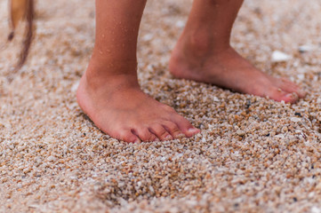 children's feet are walking on the sand