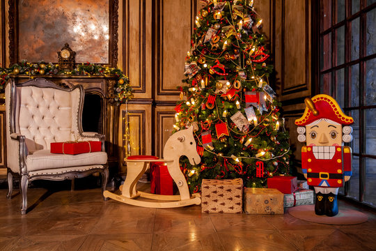 Christmas decoration in grunge room interior with fireplace, horse rocking kids chair, classic new year tree with presents