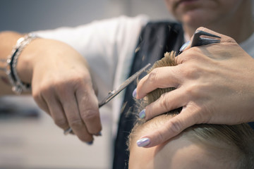 Obraz na płótnie Canvas Close up of hairdresser cutting hair of a small boy.