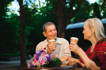 Elderly family couple talking and drinking tea ih the cafe on the street.