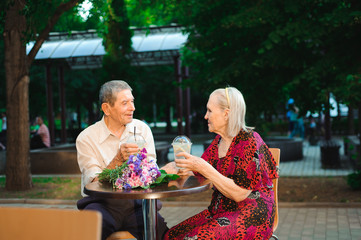 Happy elderly couple in love drinking lemonade in a cafe on the street