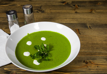 Spinach cream soup in bowl on a wooden background