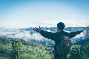 Carefree happy man enjoying nature on top of mountain cliff with sunrise. Freedom concept. Sunbeams. Enjoyment.