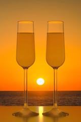 Two glasses of champagne on sunset sea background