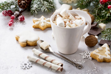 A cup of hot chocolate with marshmallows and gingerbread on a Christmas table.