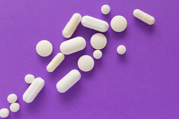 Heap of pills spreaded over color table. Group of assorted white tablets.