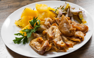 pig ears with potato and salad in plate on a wooden background