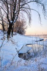 Snowy frozen landscape of sunrise on lakeside with trees
