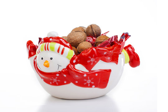 Christmas decoration. Snowman plate with candy and walnut on isolated white studio photo.
