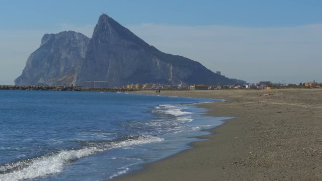 Coast of the sea on the border of Gibraltar between Spain and England. View of the Rock of Gibraltar and the beach with sea waves.