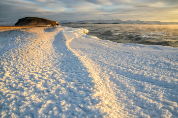 Ice floes floating on the fog water in the lake Baikal and hill. Sunset