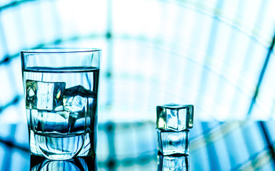 Glass of Water with ice cubes on blue Background