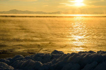 Obraz premium Ice floes floating on the fog water in the lake Baikal. Sunset