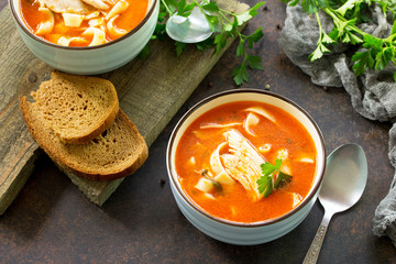 Tomato soup with pasta and chicken in a bowl on a dark stone background. The concept of healthy eating.