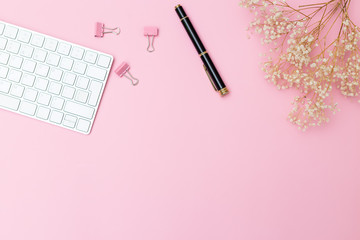 Keyboard and stationery on a pink background. Copy space