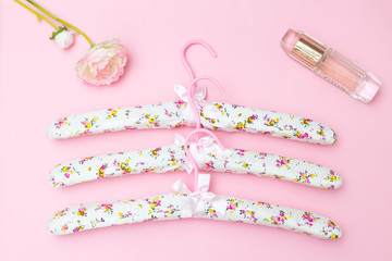 Pink hangers and female accessories on a pink background. Flat lay