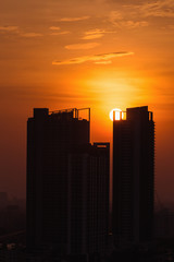 Fototapeta na wymiar Vertical scene of silhouetted tower with bright sky of golden hour with sunset at Bangkok city of Thailand.