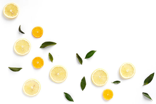  Pattern of fresh fruits on a white background, top view, flat lay. Composition of green leaves and slices of citrus fruits: lemon, mandarin. Healthy food background, wallpaper, collage.