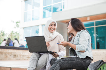 two asian college student using laptop